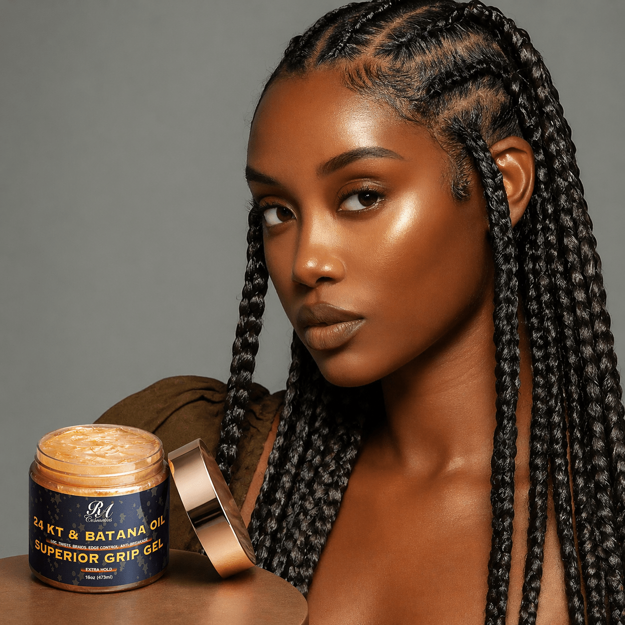 Woman with braided hair holding a jar of hair product against a gray background