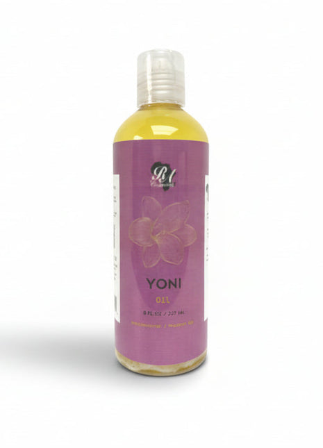 A bottle of Yoni Oil placed on a white surface, with a purple label that includes floral designs and the product name 'YONI' in bold letters.